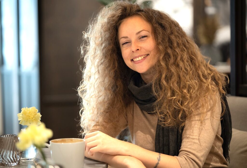 Kvinna som sitter vid bord och ler.