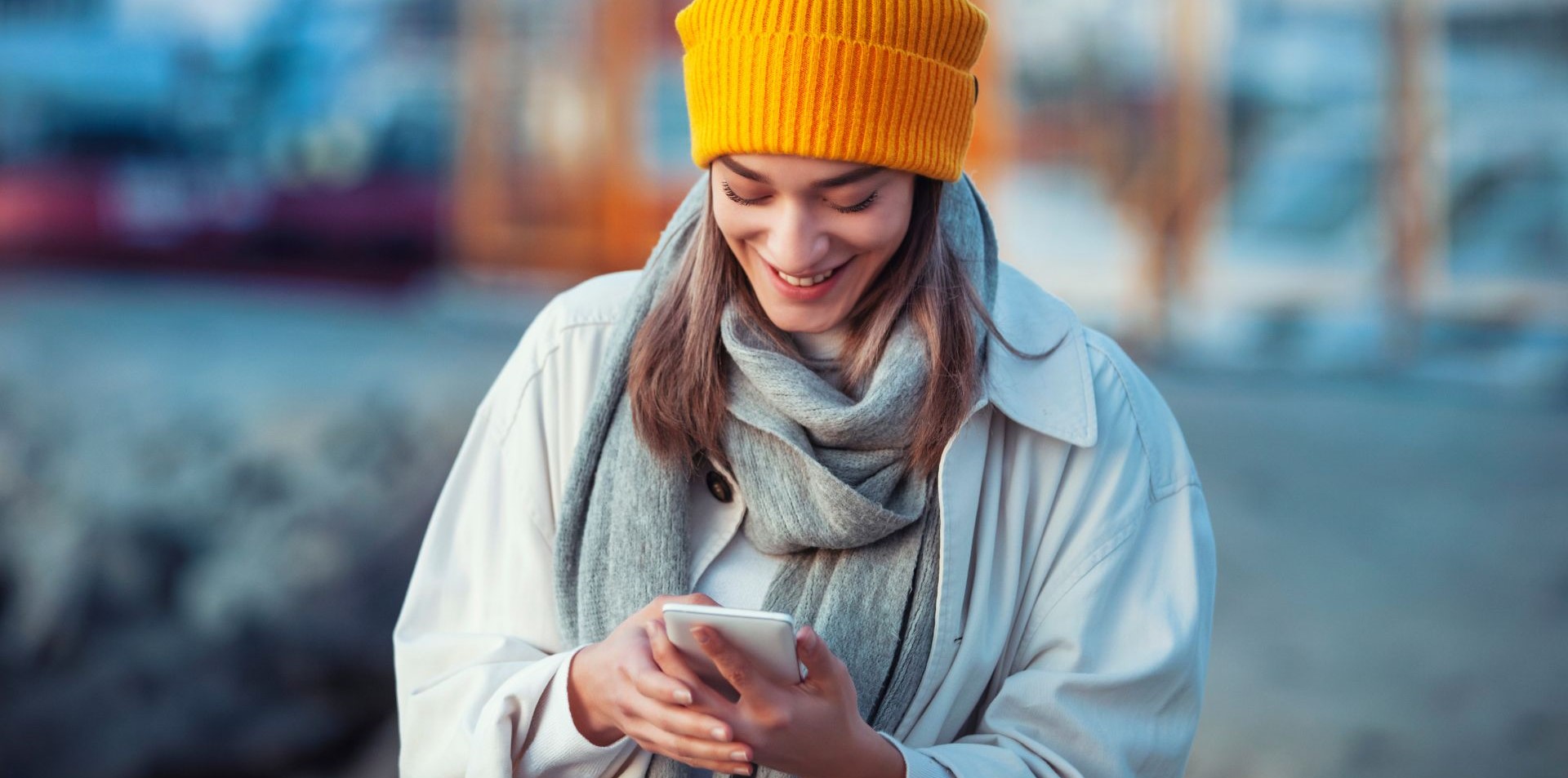 Tjej som tittar på mobilen och ler.