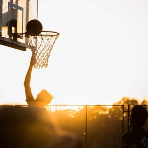 En basketspelare i rullstol gör mål i solnedgången.