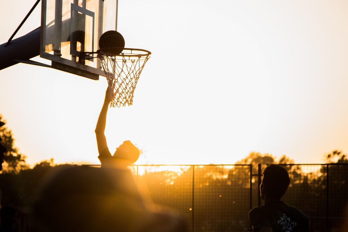En basketspelare i rullstol gör mål i solnedgången.