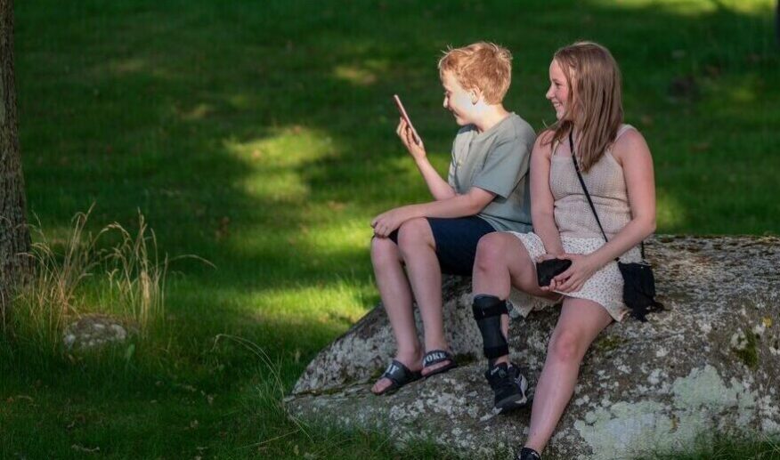 Två barn som sitter på en sten och ler.